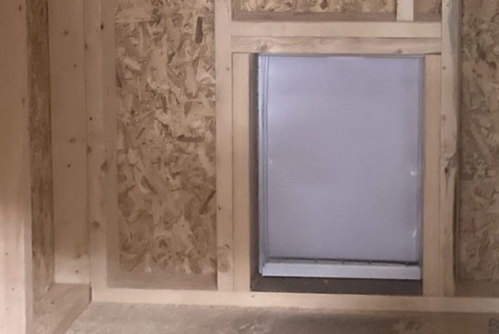 Doggie door built into the inside wall of a dog kennel run