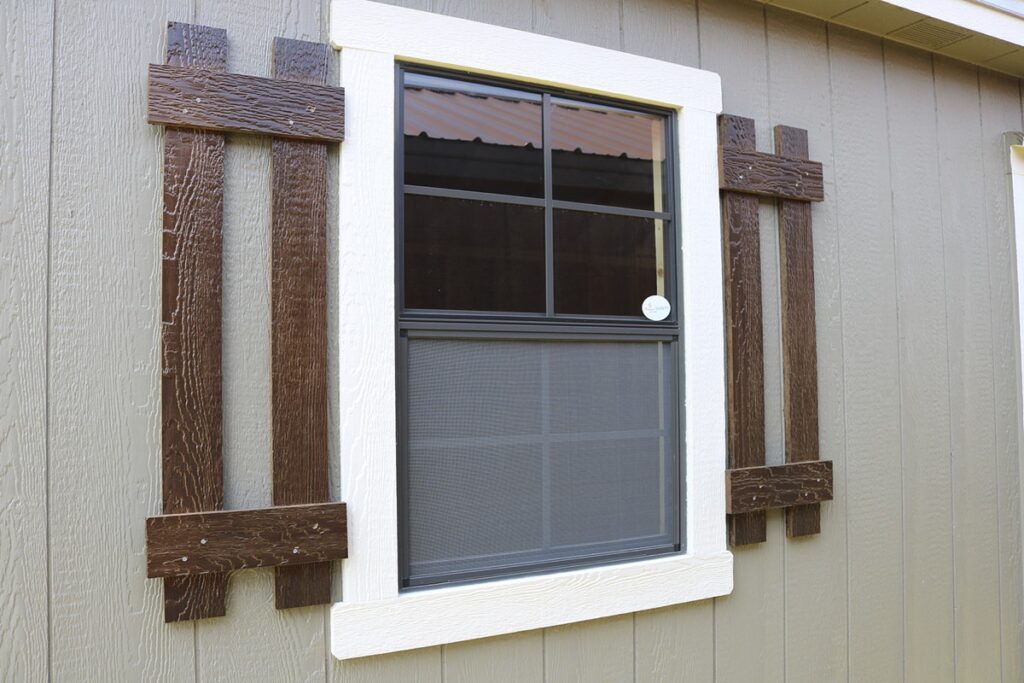 Shed window with wood shutters and white trim